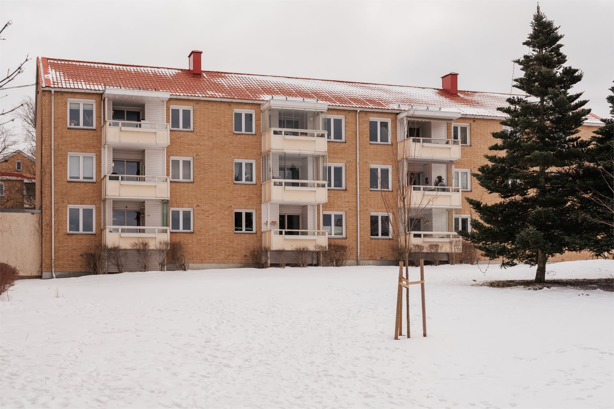 Fasaden mot baksiden viser de innglassede balkongene og borettslagets grønne fellesarealer.