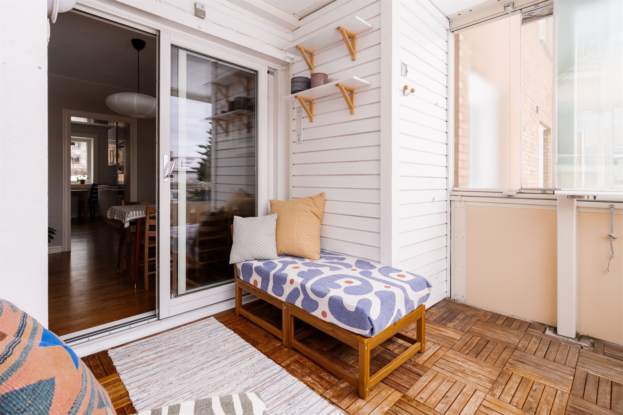 Balkongen har gulv av trelemmer og hvitmalt trekledning på veggene.