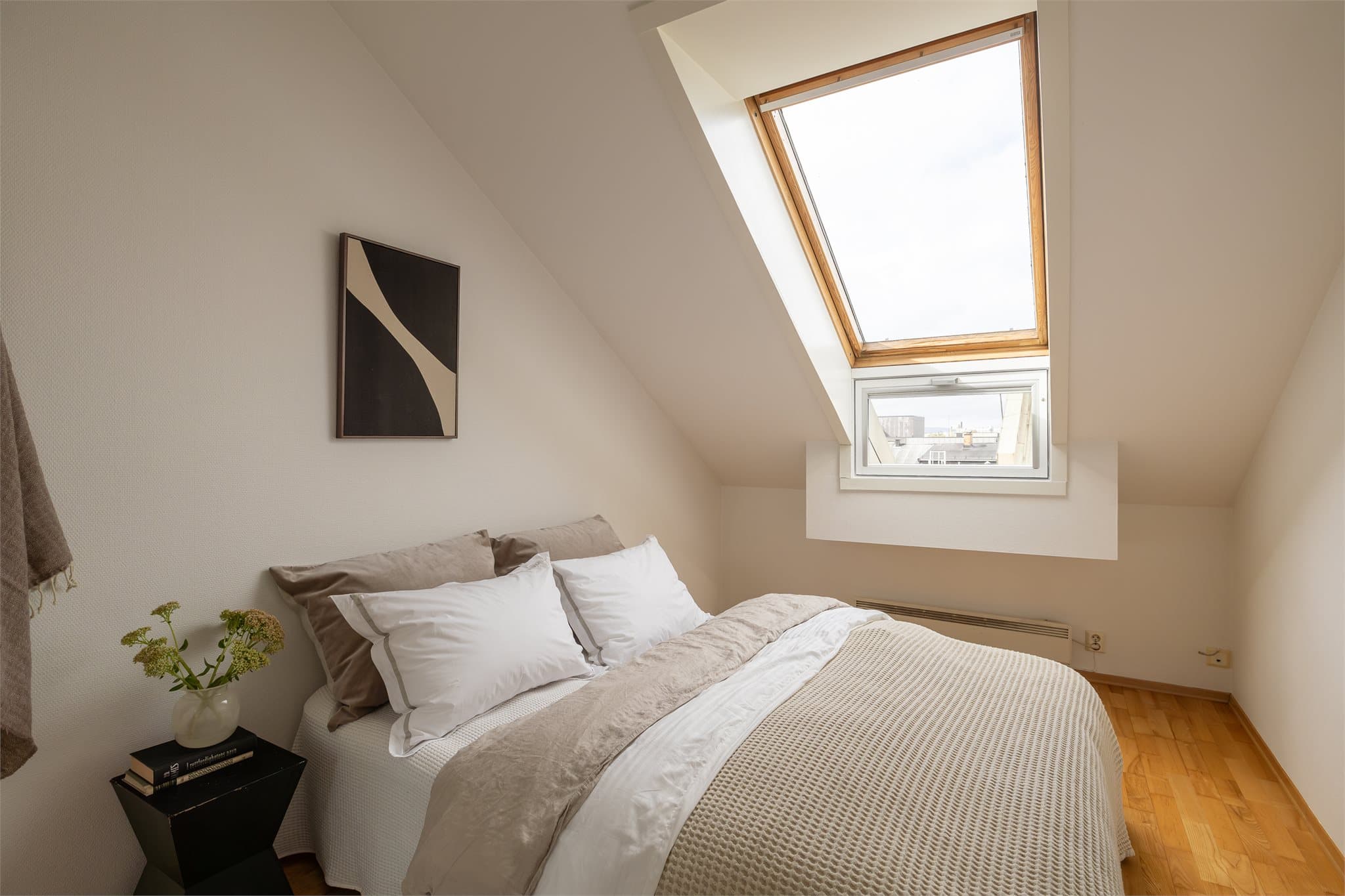 Leiligheten har et åpent soverom med skråtak og takvindu som gir både lys og luft.