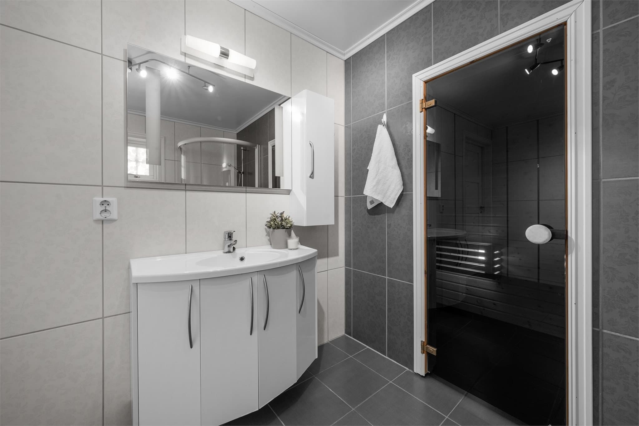 Servant på skapseksjon og speil med belysning.