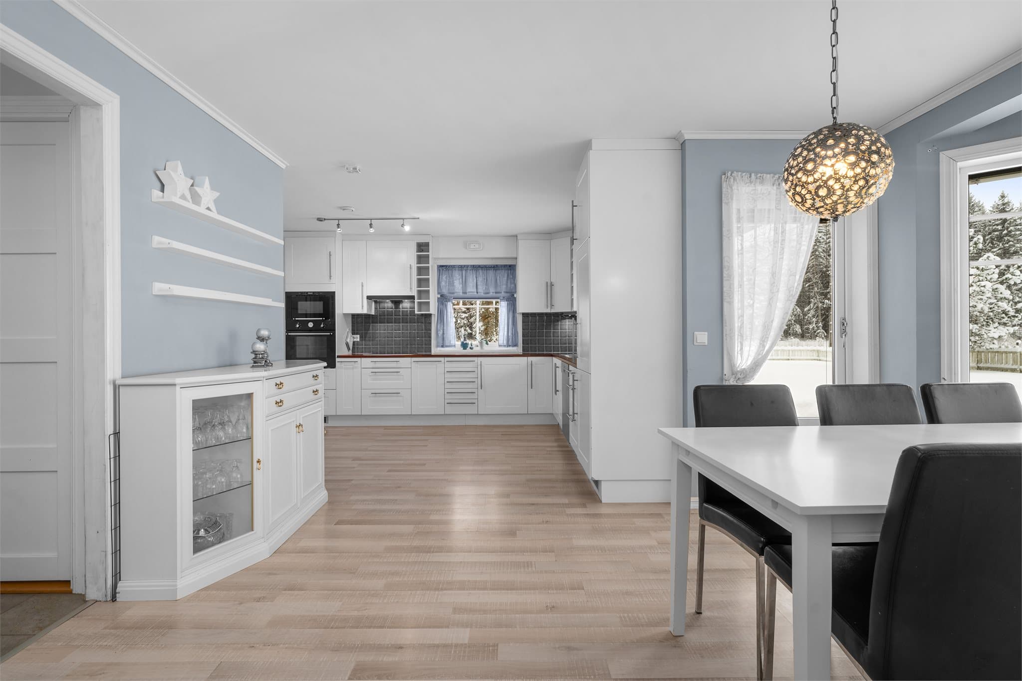 Romslig kjøkken med tidløs, klassisk profilert innredning i hvitt.