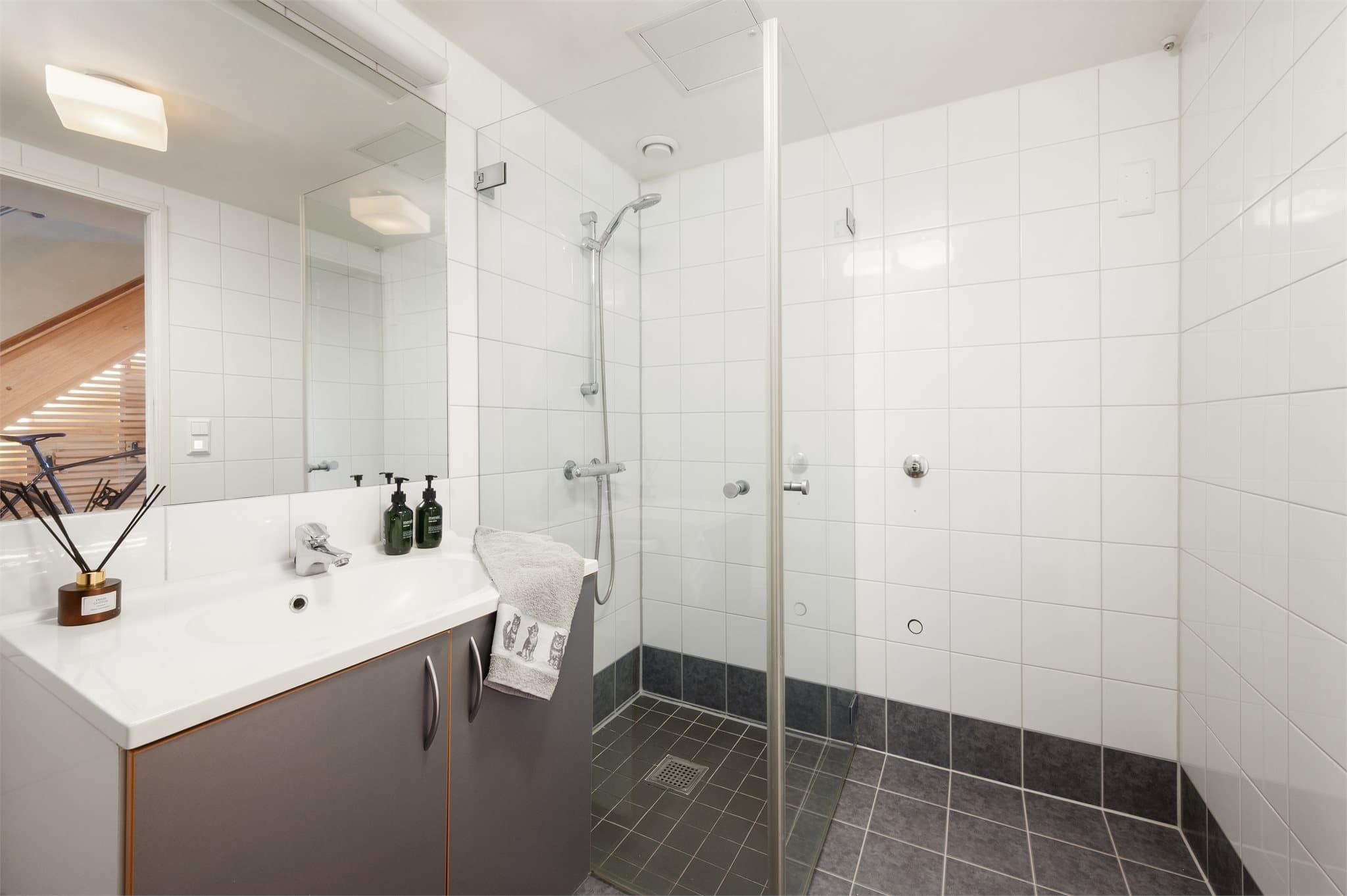 Badet i 5. etasje er flislagt og utstyrt med dusjhjørne og servantinnredning.