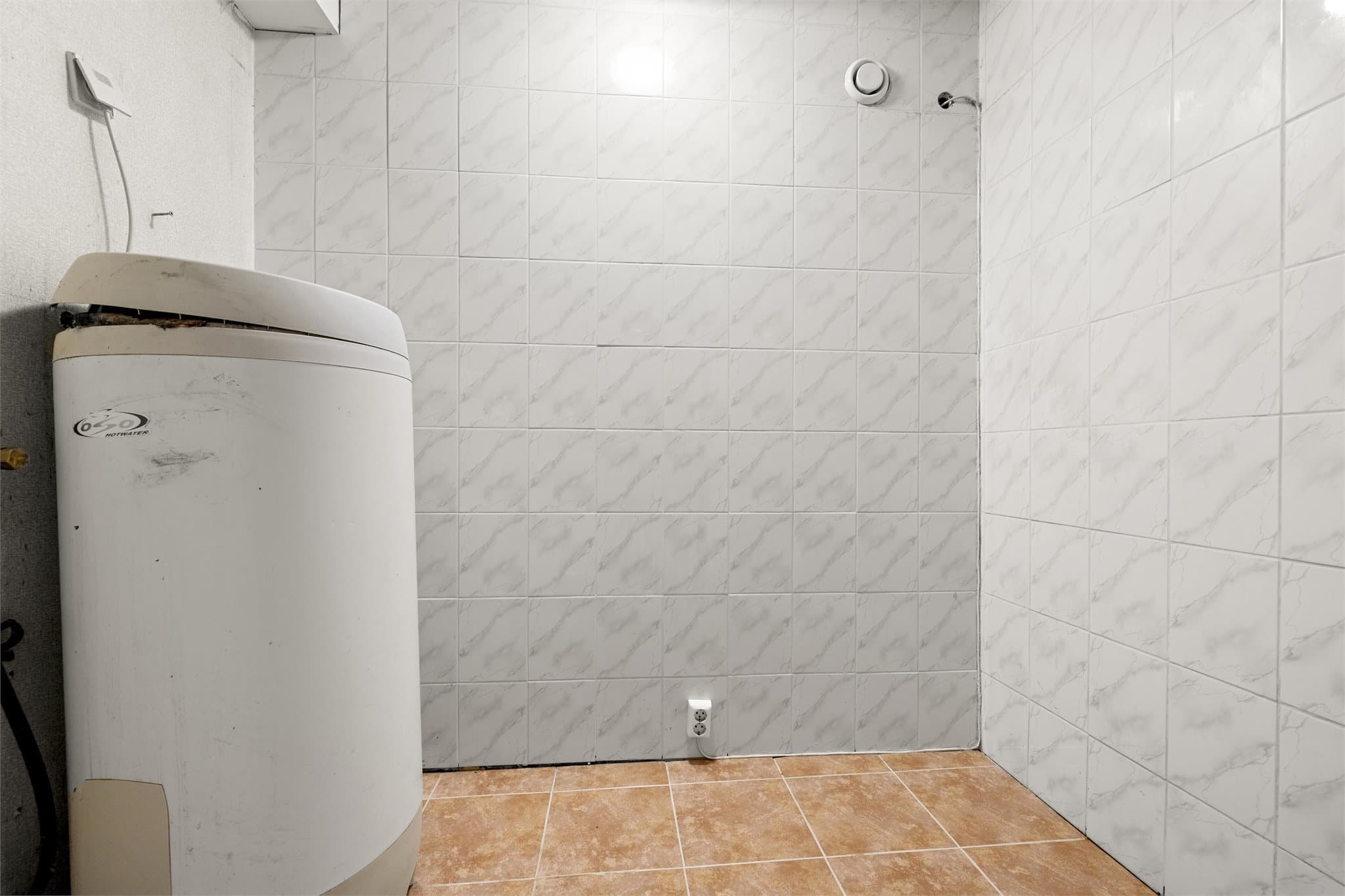 Vaskerom med opplegg for vaskemaskin og varmtvannsbereder.