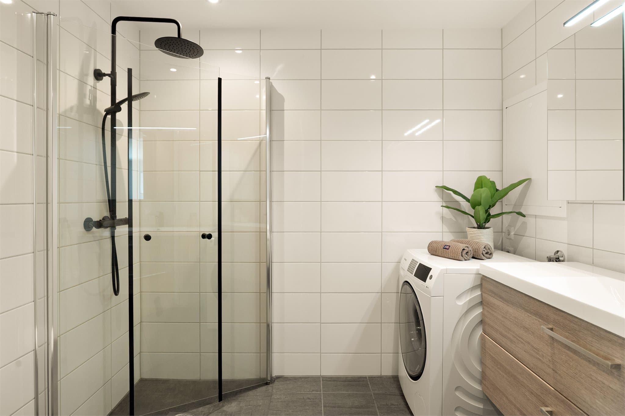 - Badet er innredet med heldekkende servant, speilskap med belysning, vegghengt toalett, dusjhjørne og opplegg for vaskemaskin -