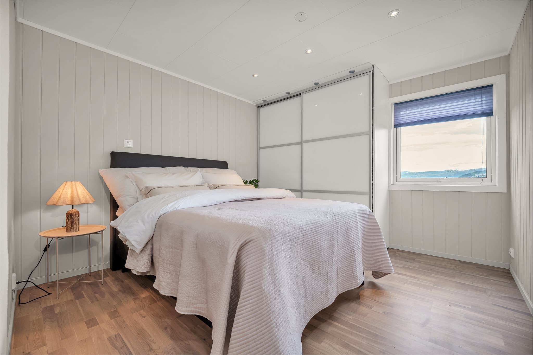 Soverom i underetasjen med panel på veggene og plass til dobbeltseng og garderobe. (Registrert som salong i byggetegninger)