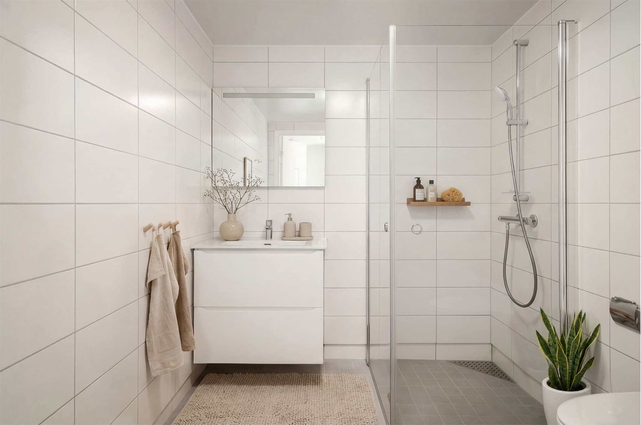 Illustrasjonsbilde - Baderommet fremstår lyst og innbydende, og er utstyrt med servantinnredning, praktisk dusjhjørne med innfellbare dusjdører og vegghengt toalett.