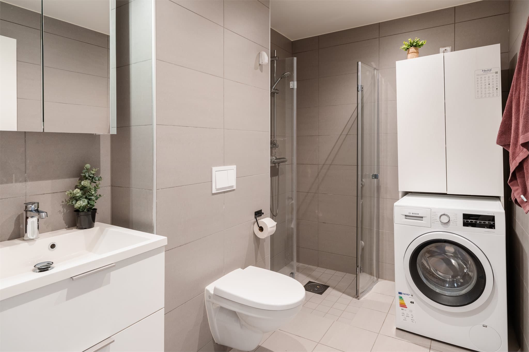 Badet har en stilren utførelse med grå 30x60 fliser på veggene og 30x30 på gulvet med gulvvarme.