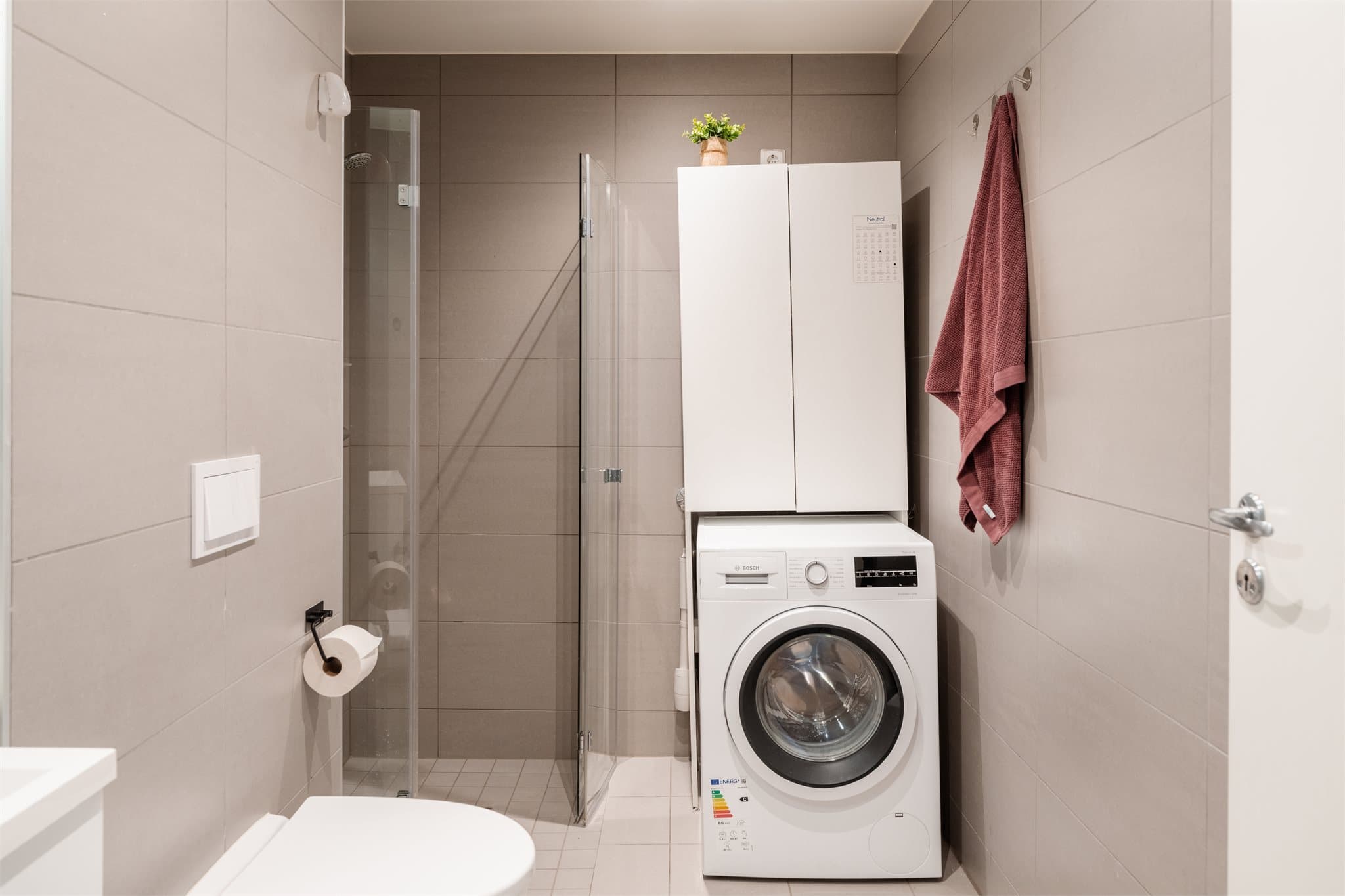 Rommet er praktisk innredet med vegghengt toalett, innfellbare dusjvegger og opplegg for vaskemaskin.