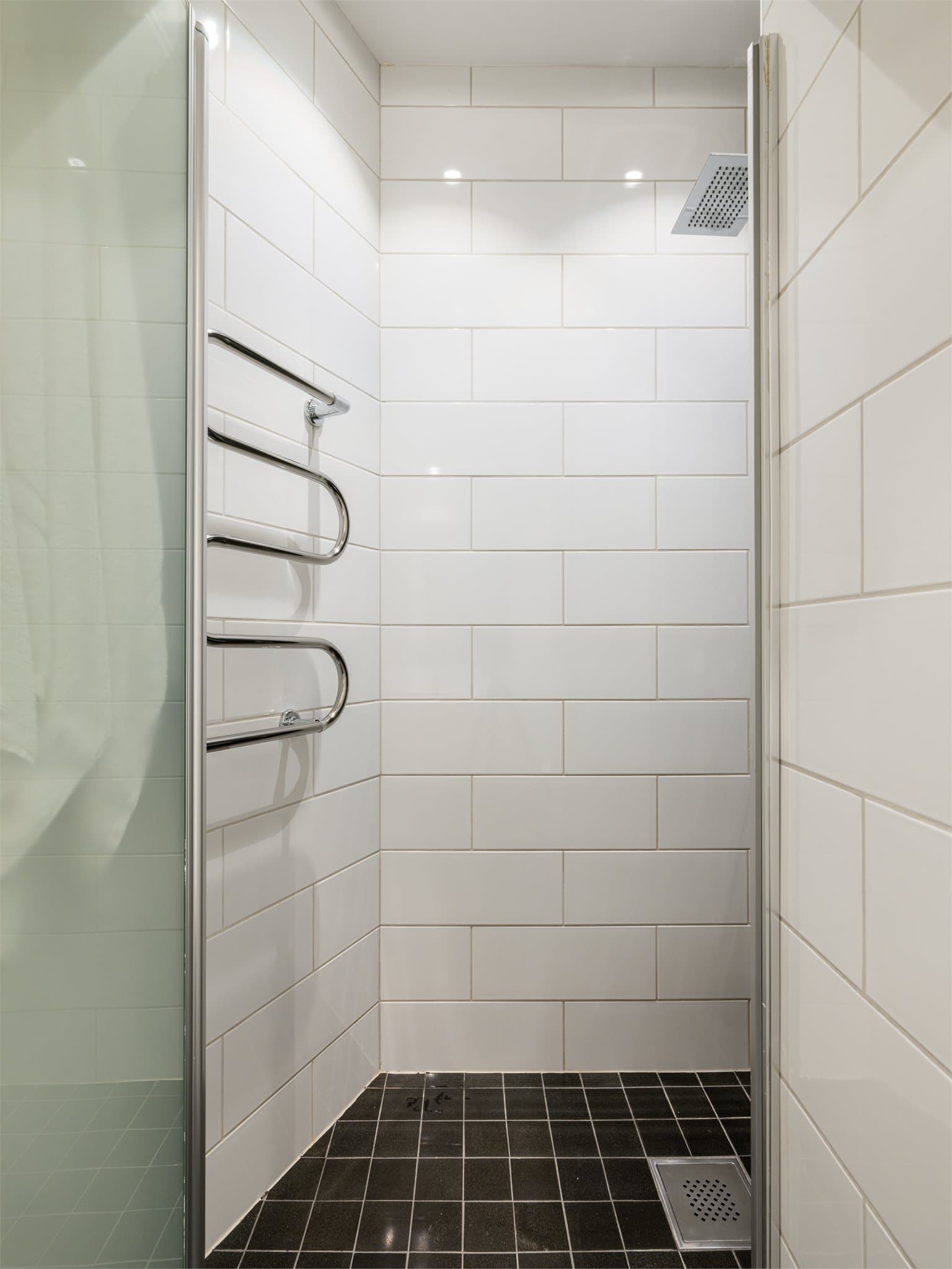 Badet har et praktisk dusjhjørne med svingbar glassdør.