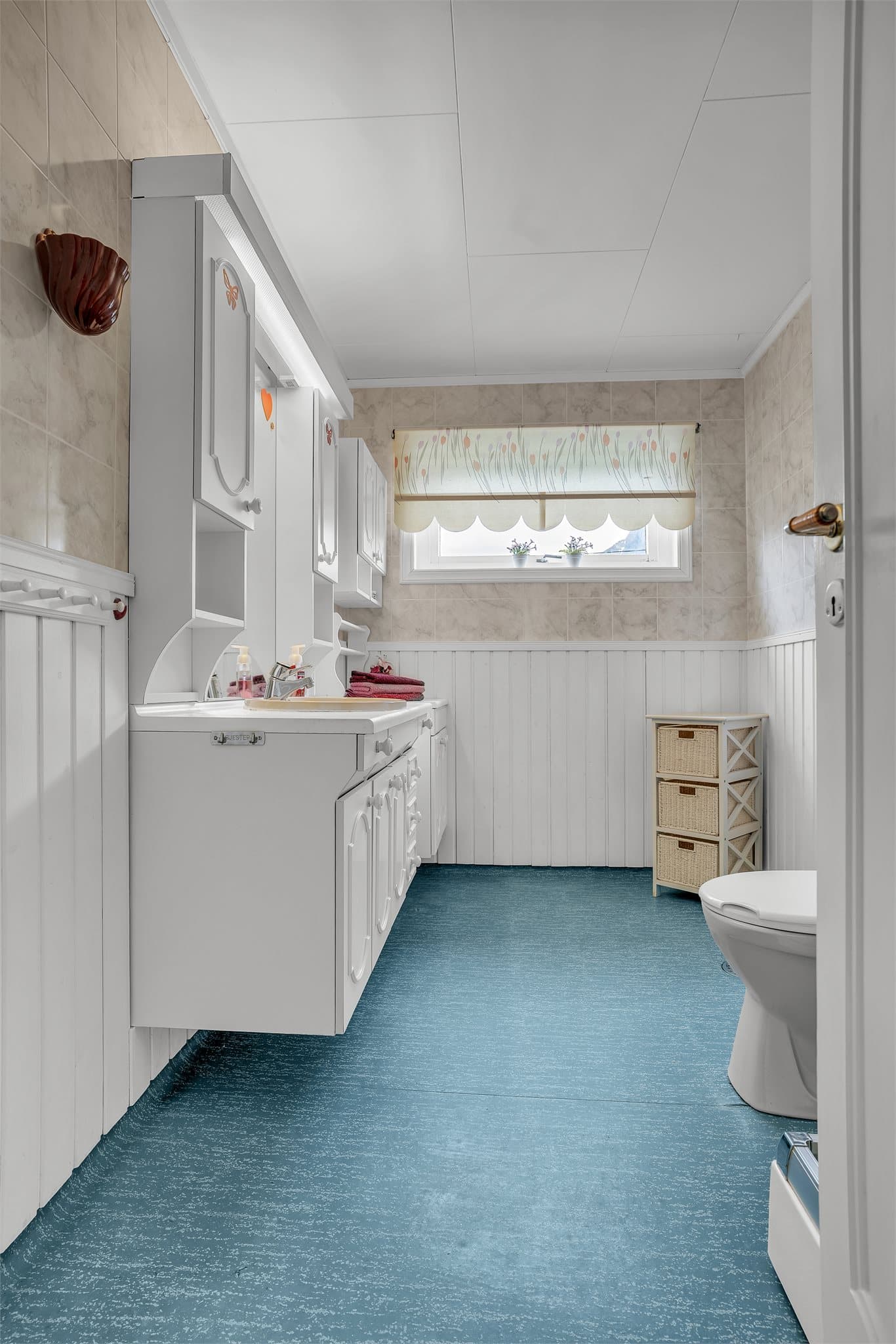 Badet i første etasje har belegg på gulv og baderomsplater på veggene.