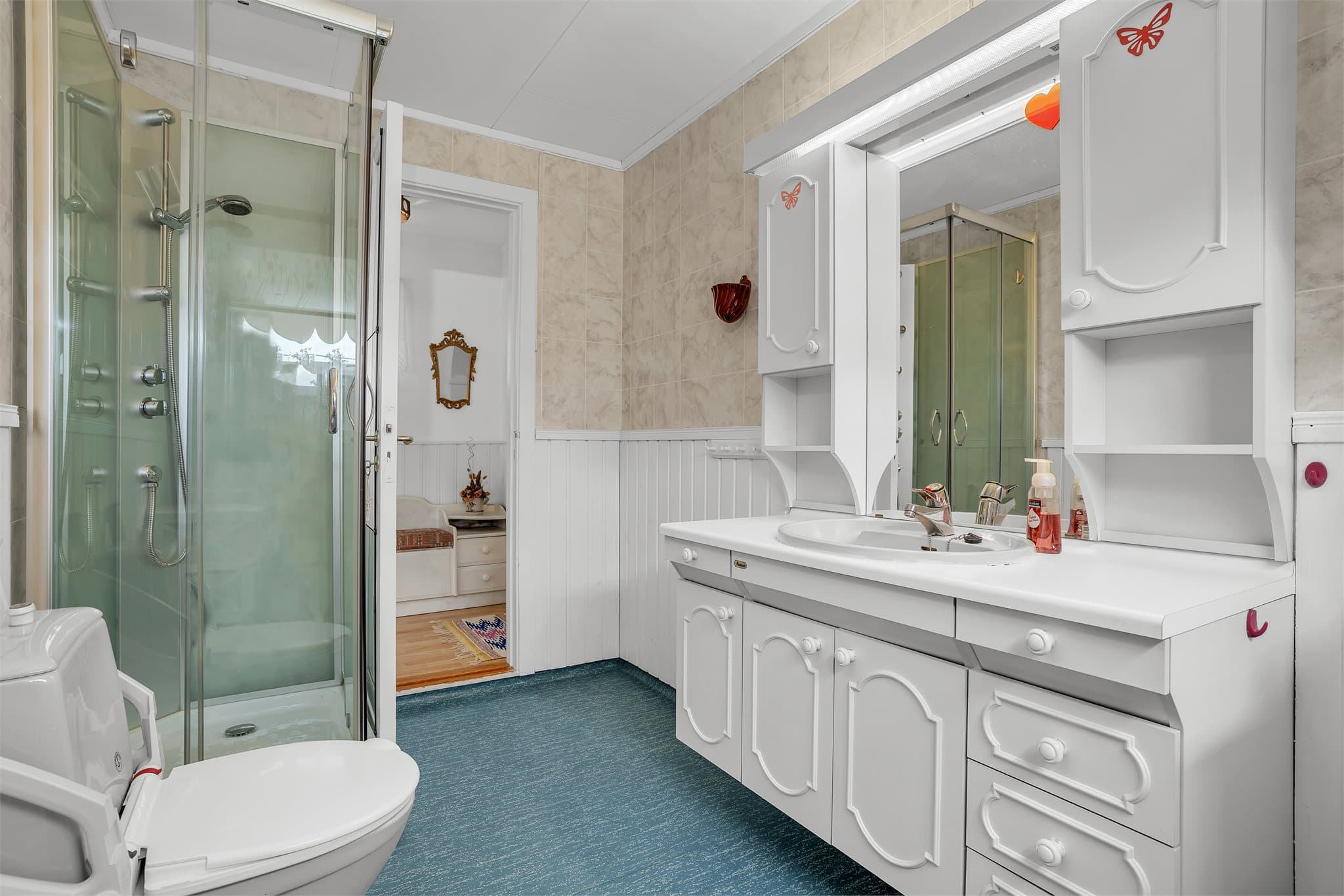 Badet er utstyrt med dusjkabinett, toalett og servantinnredning.