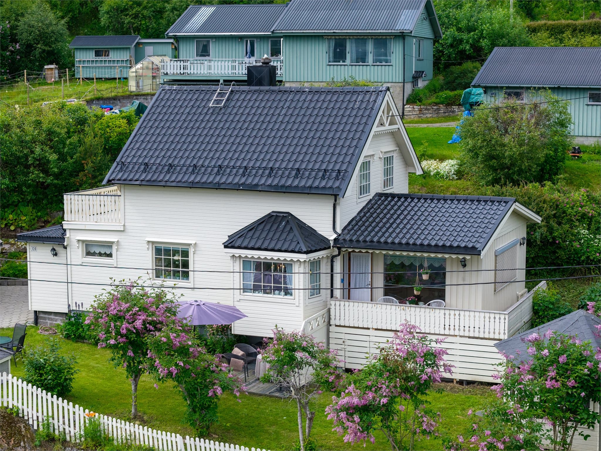 Boligen sett fra siden, med karnapp og overbygd veranda.