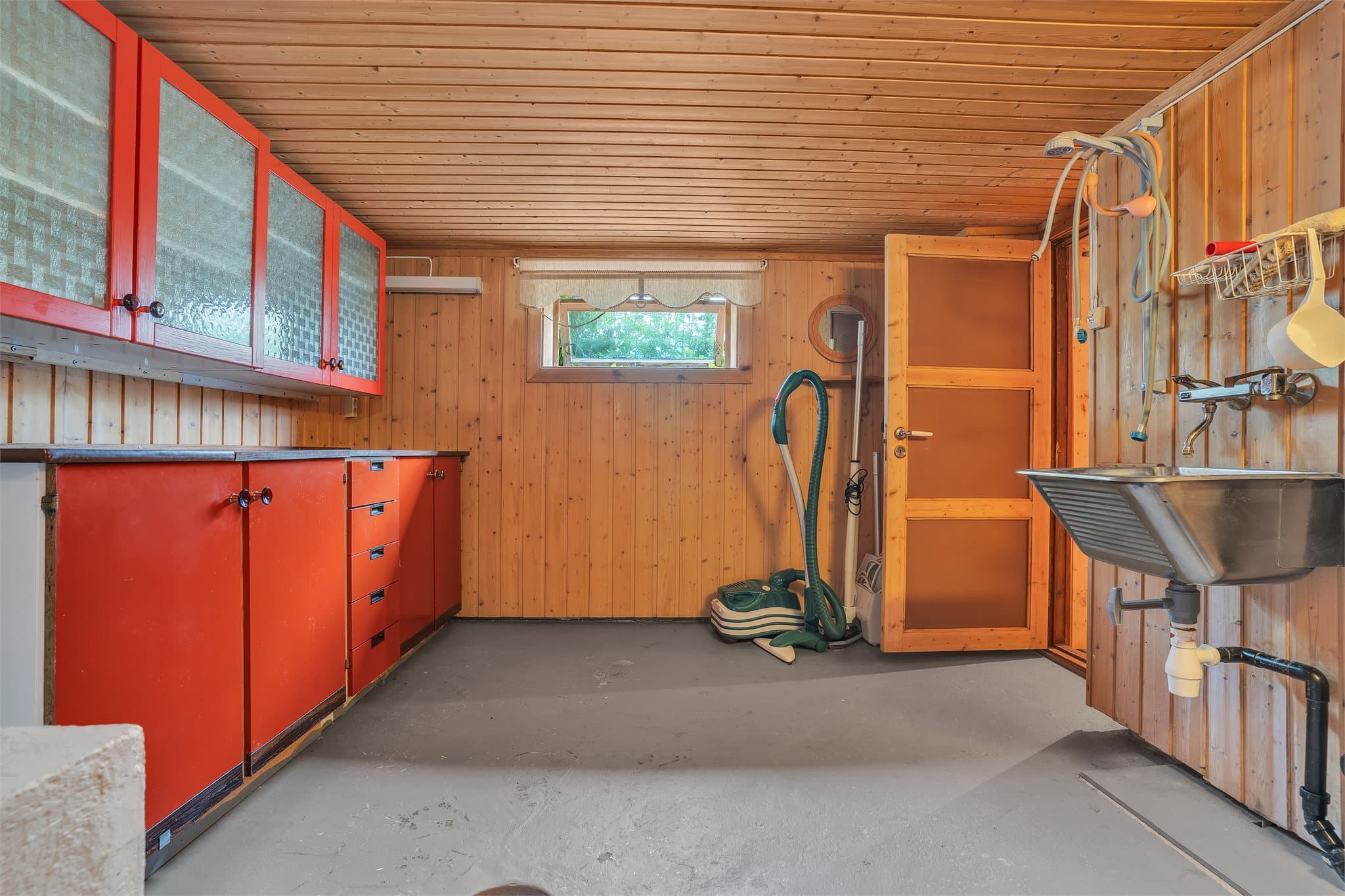 Praktisk vaskerom i kjeller med betonggulv og opplegg for vaskemaskin.
