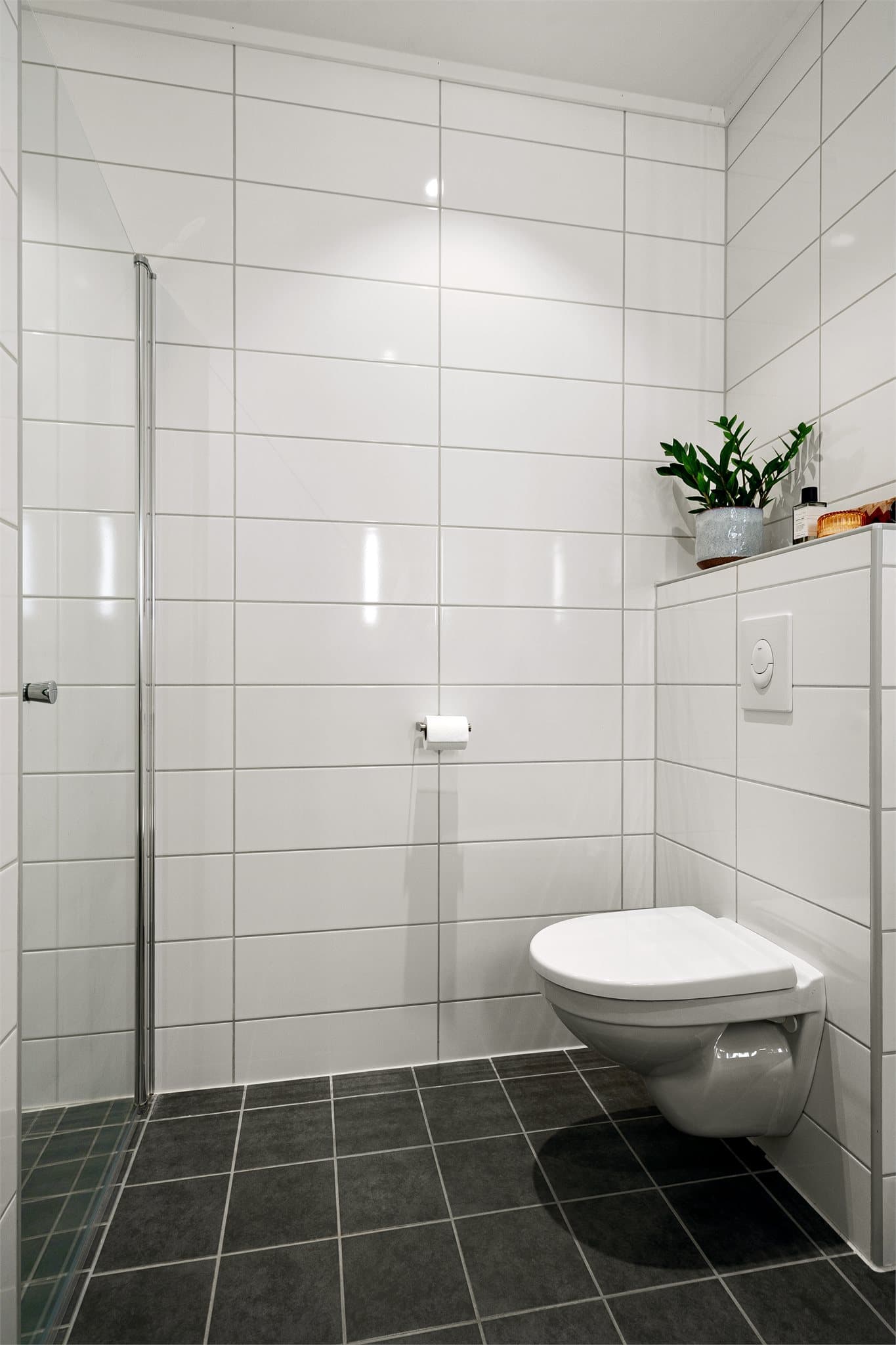 Badet har flislagt gulv med elektrisk gulvvarme, flislagte vegger og vegghengt toalett.