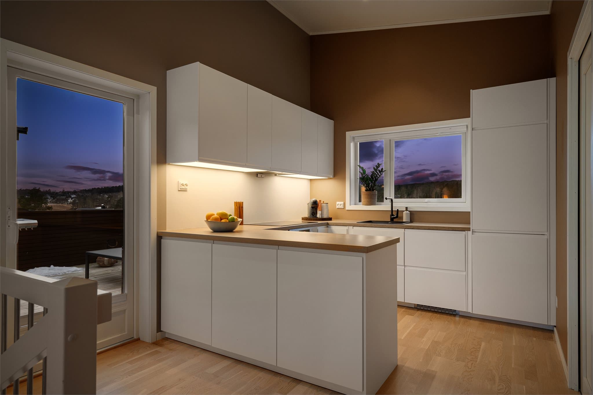 Kjøkkenet har en stilren og moderne innredning med glatte fronter og en praktisk laminatbenkeplate.