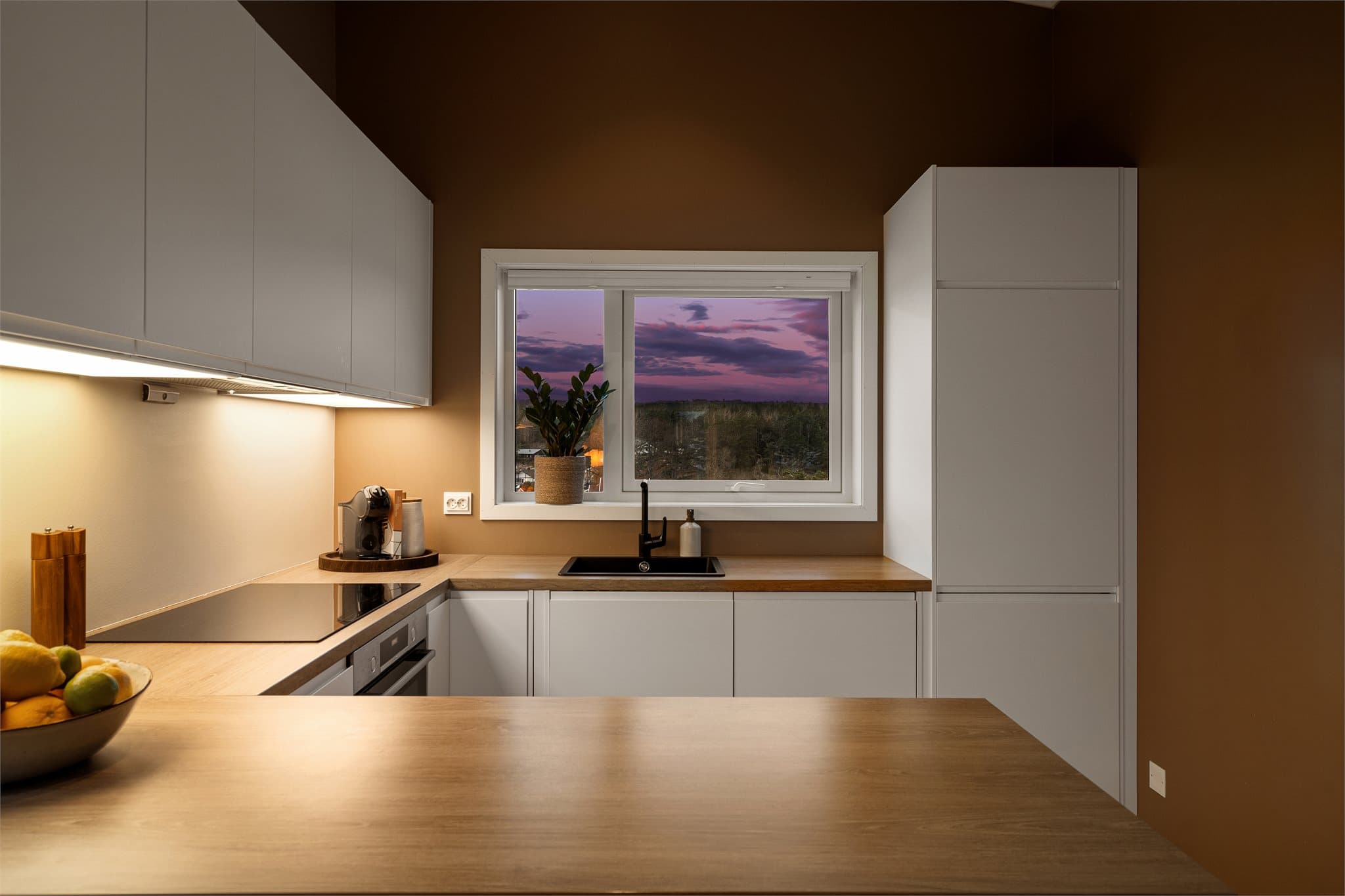 Kjøkkenet er av god størrelse og har en stilren innredning med glatte fronter og laminatbenkeplate. Alle hvitevarer er integrert.